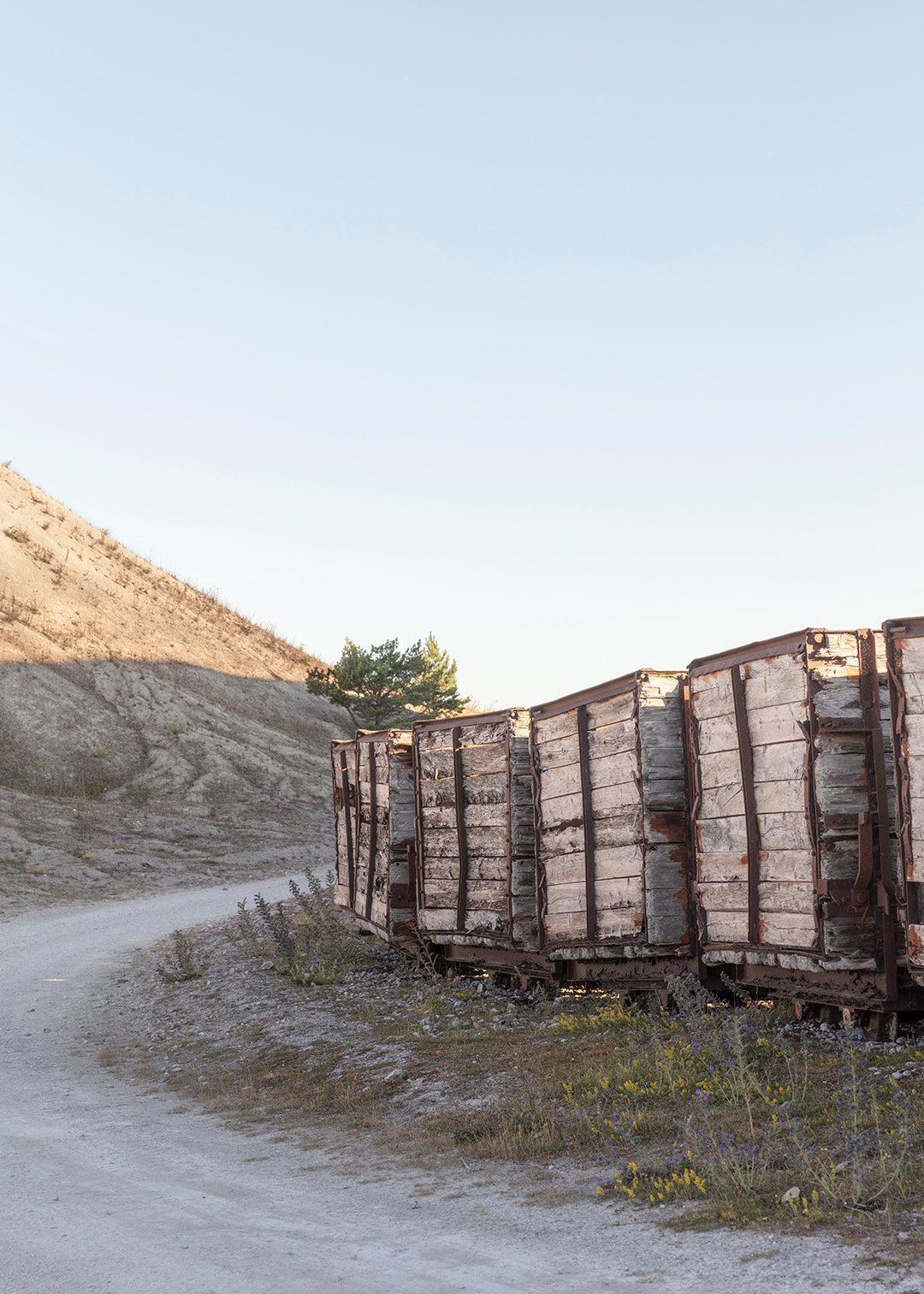 Gamle togvogne langs en kurvet vej i fabriksområdet ved Fabriken Furillen på Gotland.