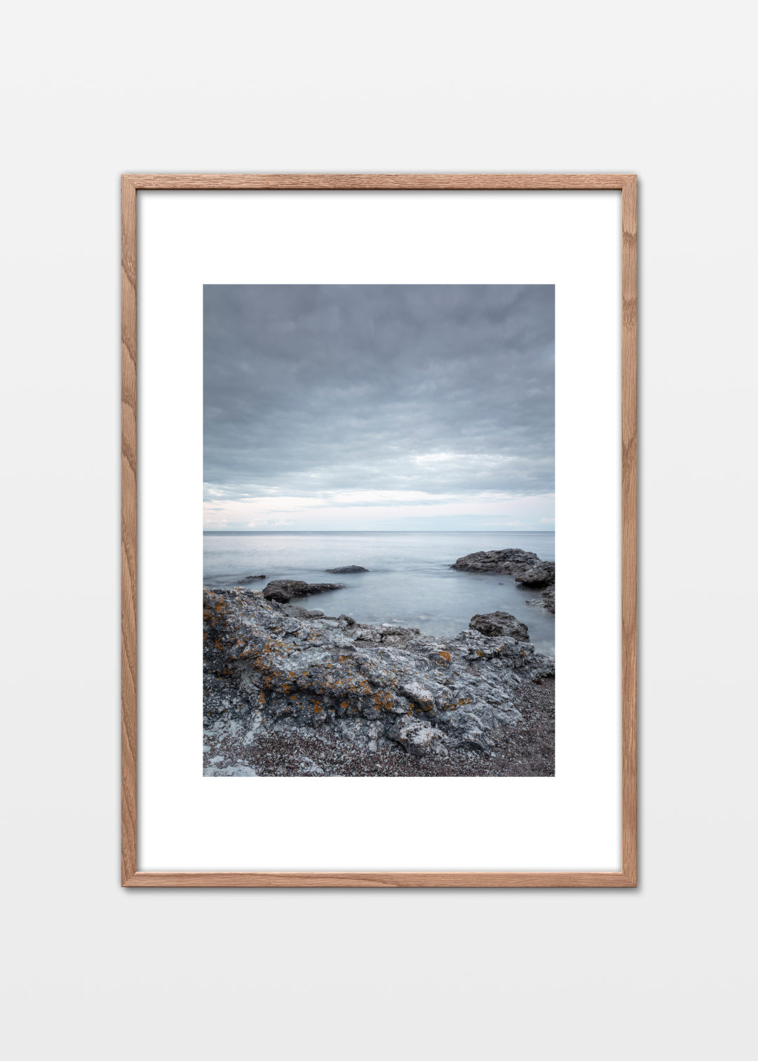 Dramatisk klippekyst på Gotland med grå klipper, lav og roligt hav under skydækket himmel.