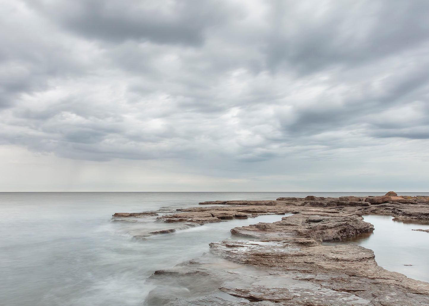 Foto af Gotlands lyse klipper og stille hav med dramatiske skyer – foto Martin Bay.