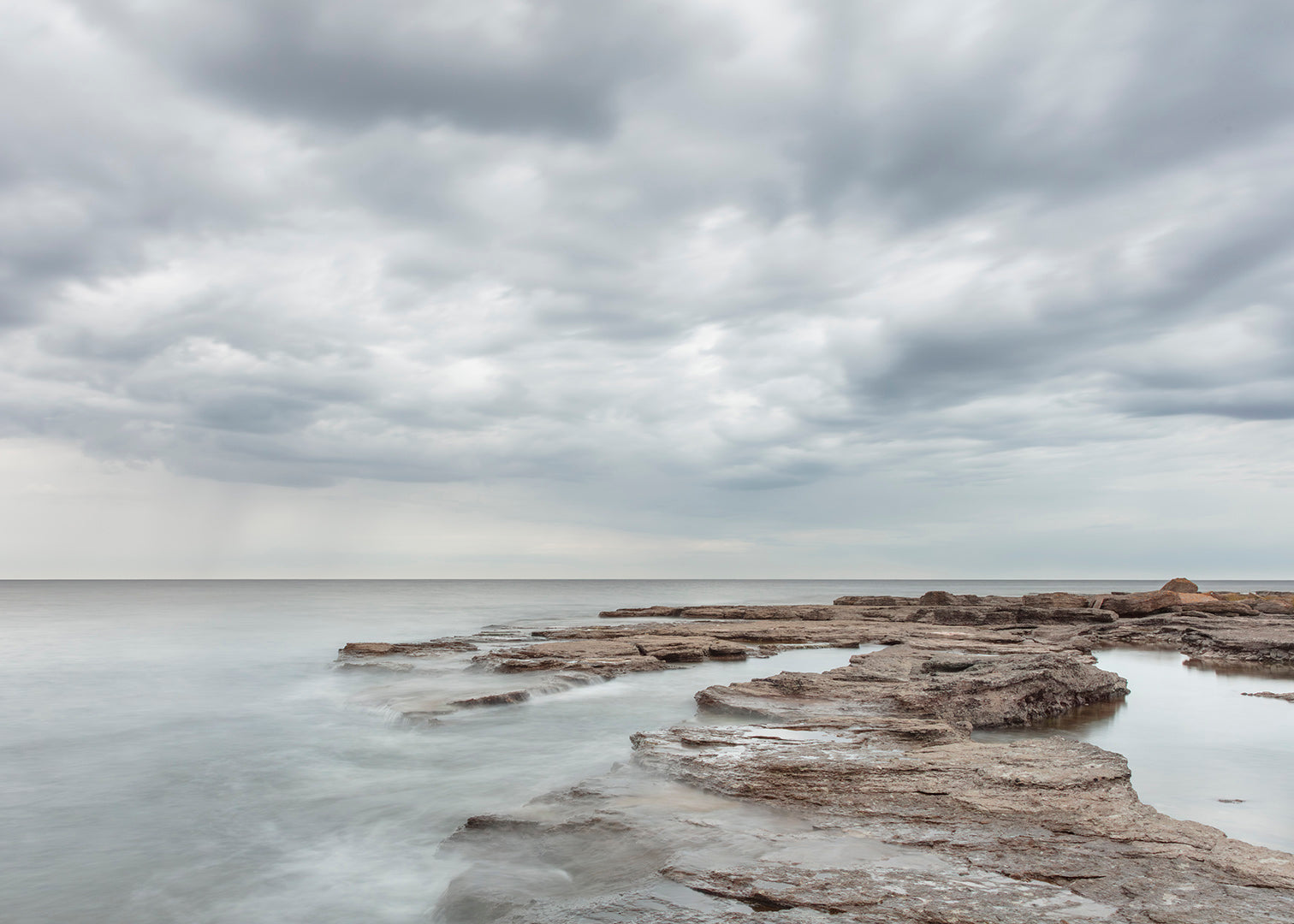 Foto af Gotlands lyse klipper og stille hav med dramatiske skyer – foto Martin Bay.