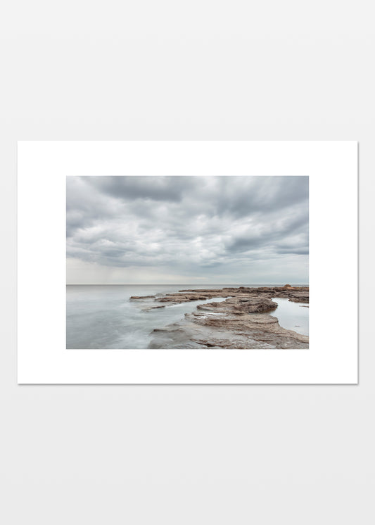 Fotoplakat af Gotlands lyse klipper og stille hav med dramatiske skyer – foto Martin Bay.