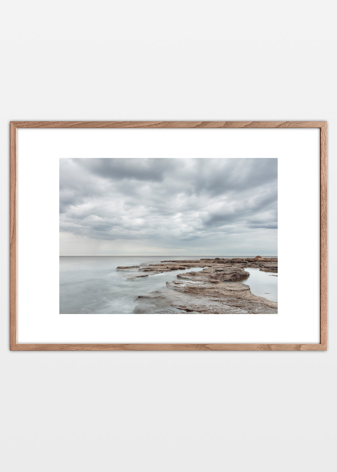 Fotoplakat af Gotlands lyse klipper og stille hav med dramatiske skyer – foto Martin Bay.