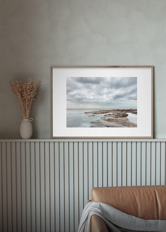 Fotoplakat af Gotlands lyse klipper og stille hav med dramatiske skyer – foto Martin Bay.