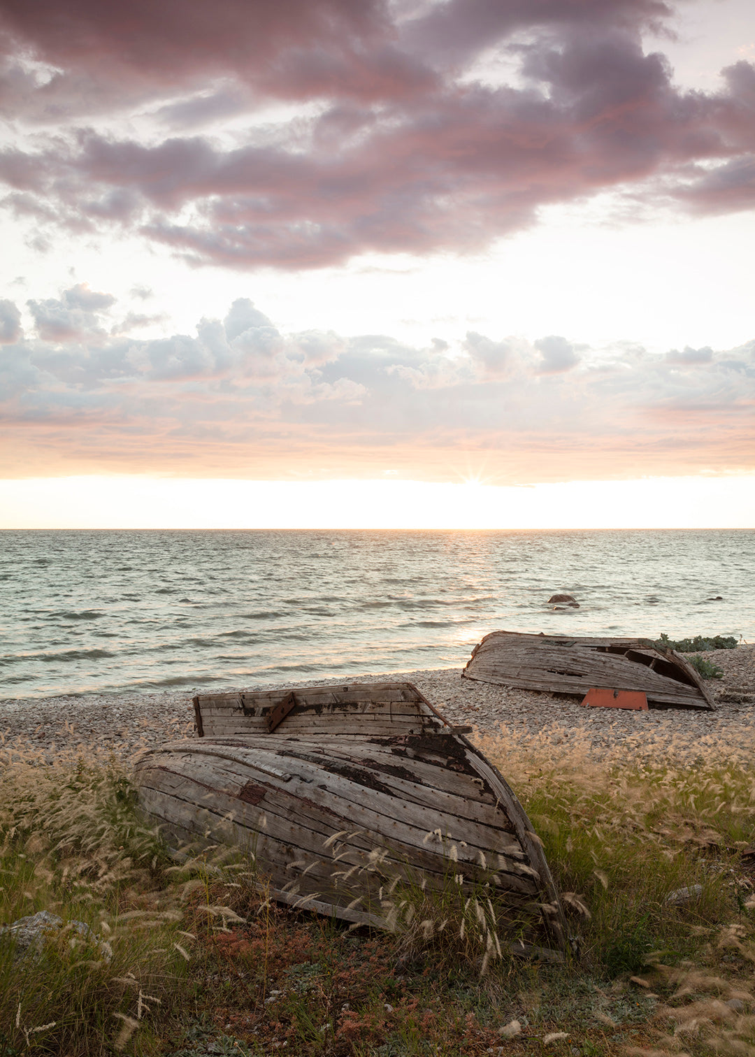 Fotografi af træbåde på stranden ved solnedgang på Gotland.