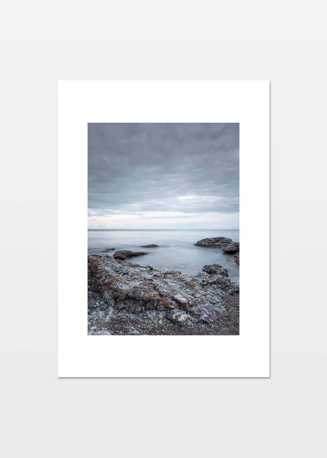 Dramatisk klippekyst på Gotland med grå klipper, lav og roligt hav under skydækket himmel.
