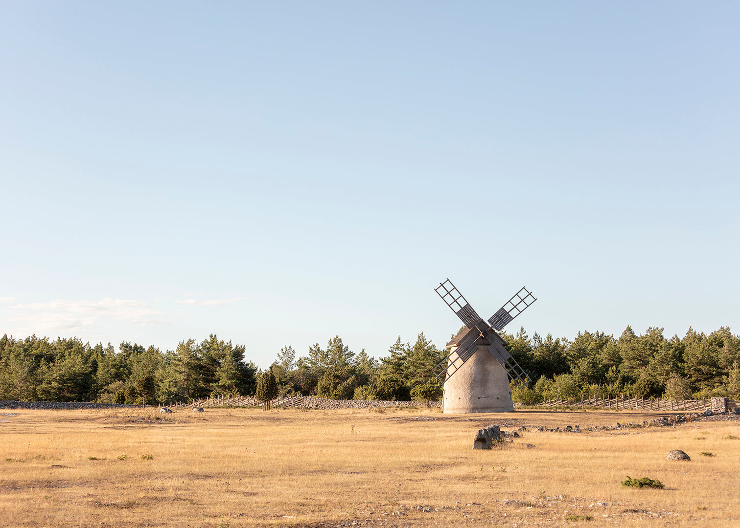 Fotografi af vindmølle i åbent sommerlandskab på Gotland med blå himmel.